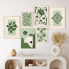 a white table topped with pictures and vases next to a wall filled with plants