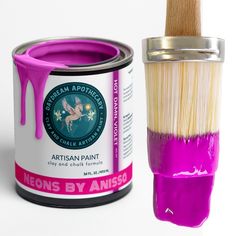 a paint can and brush with purple glaze on it next to a white background