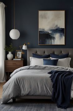 a bedroom with blue walls and grey bedding, artwork on the wall above it