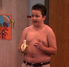 a shirtless man holding a banana in his hand