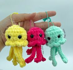 three small crocheted octopus keychains are being held by a person's hand