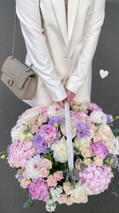 a woman holding a bouquet of flowers with her hands on the handle of an umbrella