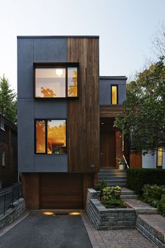 a modern house with two story windows and brick walkway leading up to the front door