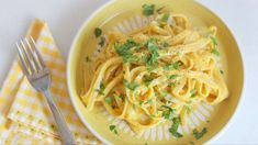 a yellow plate topped with pasta and parsley on top of a checkered napkin