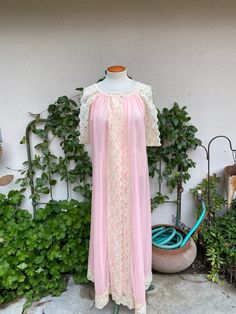 Gorgeous 1960's-1970's vintage pink robe/gown with wide cream lace trim.  Two buttons across the neckline with an open front.  Sleeveless with deep arm holes.  Double layer of fabric.  (Pics to the fabric is typical for these gowns.  I examined it carefully and didn't notice any.)  Well cared for.  Excellent vintage condition - practically mint! label:  Tosca Lingerie fabric:  nylon size:  labeled size is medium.  Based on the open style of this gown, it may fit multiple sizes.  Shown on a dress Pink Lace Nightgown With Delicate Details, Vintage Pink Sleepwear, Pink Sheer Vintage Nightgown, Pink Sleeveless Vintage Nightgown, Vintage Pink Sheer Nightgown, Vintage Sheer Pink Nightgown, Vintage Pink Nightgown For Spring, Vintage Lace Trim Dresses For Loungewear, Vintage Pink Sleepwear For Wedding Night