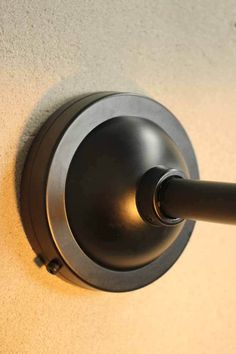 a close up of a black handle on a wall mounted toilet paper dispenser