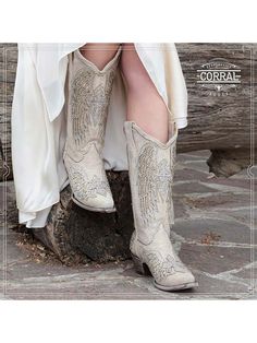 Introducing the Corral Women's Wing & Cross Studded Wedding Boots - the ultimate statement piece for brides who dare to be different. These exquisite white boots are designed to elevate your wedding style, taking you beyond the traditional and into a realm of bold, modern chic. Crafted from premium white leather, these wedding boots showcase an intricate wing and cross design brought to life by a stunning white glitter overlay. The silver studs sprinkled throughout the design exude sophisticatio White Low Heel Party Boots, White Low Heel Boots For Party, Elegant Wedding Boots Embellished, Elegant Embellished Wedding Boots, Glamorous Embellished Wedding Boots, Elegant Embellished White Boots, Elegant Fitted Wedding Boots, White Embellished Snip Toe Boots, White Embellished Boots With Pointed Toe