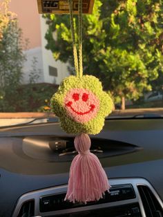 a car dashboard with a smiling face hanging from the dash board and tassels