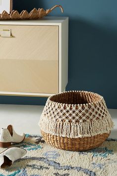 a pair of shoes sitting on top of a rug next to a basket and dresser