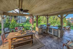 an outdoor kitchen and dining area is shown in this image, with the grill on the far side