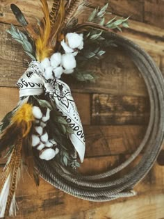 a wreath with cotton and feathers on top of a wooden table next to a rope