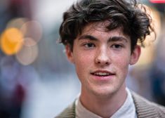 a close up of a person wearing a suit and tie with hair in the wind