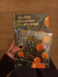 a person holding up a cd with oranges on the front and back cover in their hands