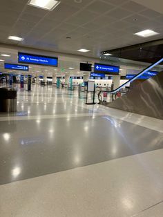 an empty airport with luggage carts and blue signs on the wall above them, as seen from the ground