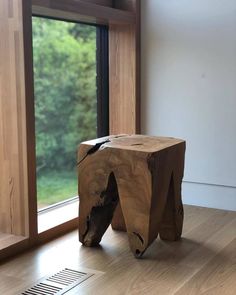 a wooden stool sitting in front of a window on top of a hard wood floor