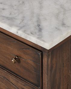 a marble top on a wooden dresser with brass pulls and knobs in an antique finish