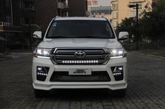 the front end of a white suv parked on a brick road