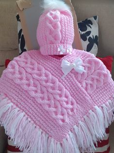 a pink knitted blanket with a white bow on it