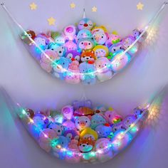 there are many stuffed animals in the hammock with lights around them and stars on the wall