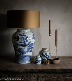 a blue and white vase sitting on top of a wooden table next to a lamp