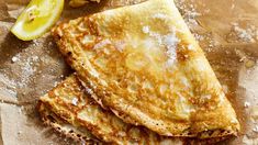 three pieces of toast with powdered sugar on top and lemons in the background