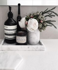 a bathroom sink with soap, lotion and flowers on the counter next to it