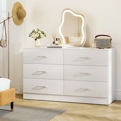 a bedroom with a white dresser, mirror and lamp on it's side table