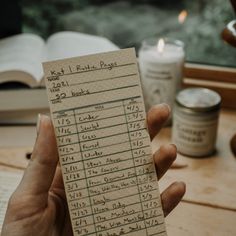 a person holding up a piece of paper with some writing on it and candles in the background