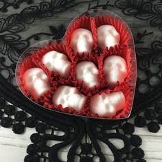 a heart shaped box filled with white chocolates on top of a lace tablecloth