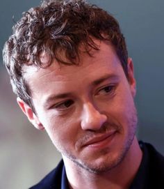 a close up of a person wearing a black shirt and tie with his eyes closed