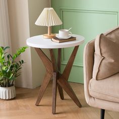 a small table with a lamp on it next to a chair and potted plant