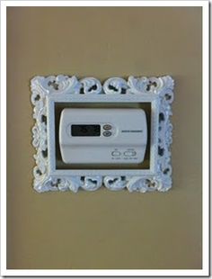 an electronic device mounted to the side of a wall in a white frame with ornate designs