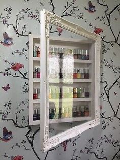 a mirror is hanging on the wall above a shelf with bottles and spices in it