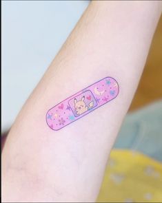 a person with a tattoo on their arm has a pink pill shaped like a cat