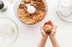 two hands holding something in front of a food processor