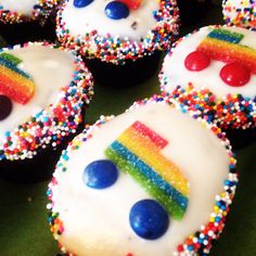 some cupcakes with white frosting and rainbow decorations