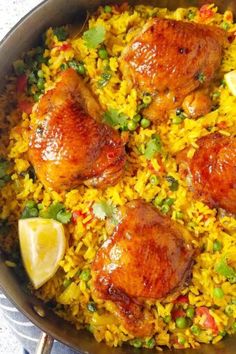 chicken and rice dish in a pan with lemon wedges