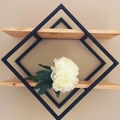 a white flower sitting on top of a wooden shelf next to a wall mounted object