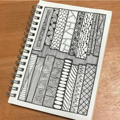 a spiral notebook with an abstract design on the front and back cover, sitting on top of a wooden table