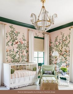 a baby's room with pink and green wallpaper, white crib, chandelier, and rocking chair