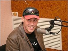 a man with a hat on sitting in front of a microphone and wearing a baseball cap