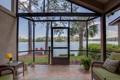 the inside of a house with glass walls and doors leading out to a body of water