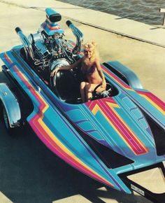 a dog is sitting in the front seat of a colorful car with a motorcycle on it