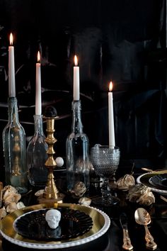 a table topped with bottles and candles next to plates filled with food on top of it