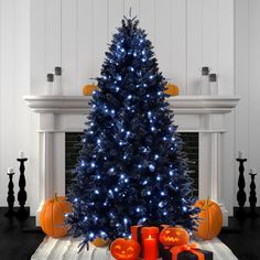 a decorated christmas tree with blue lights and pumpkins in front of a fire place