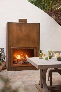 an outdoor fireplace is shown with pots on the table and potted plants next to it