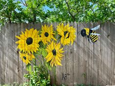 a painting of sunflowers and a bee on a fence