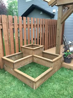 a wooden planter sitting on top of a lush green field next to a fence