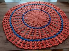 a crocheted doily on a wooden table with a window in the background