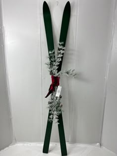 pair of skis decorated with pine branches and red ribbon hanging on wall in room